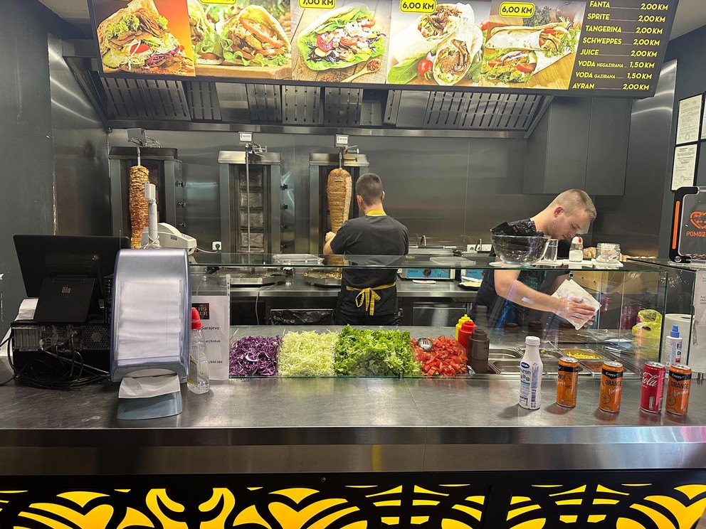 two employees at a döner shop prepare an order