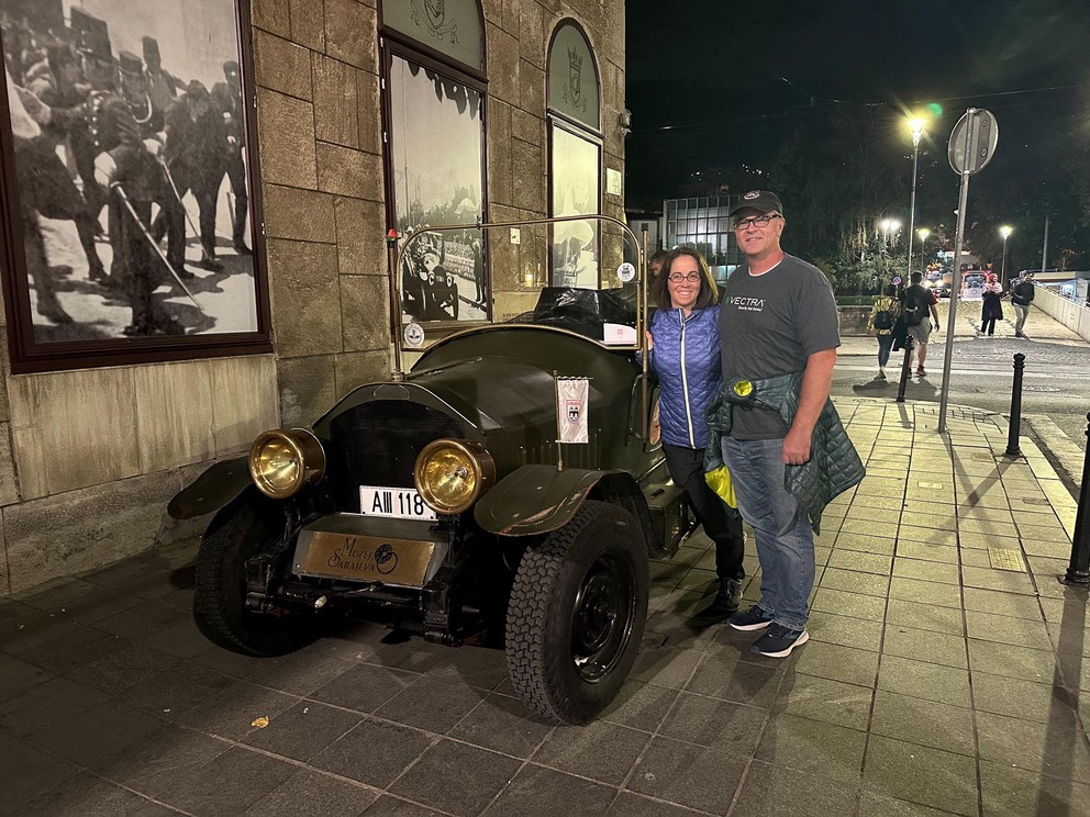 a couple stand next to replica of the car where Archduke Franz Ferdinand was assisinated